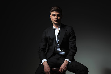 portrait of groom with open collar and undone bowtie sitting