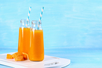 Pumpkin smoothie bottled. Pumpkin juice on a blue table. Autumn drinks.