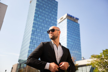 Handsome elegant businessman with sunglasses in front of office building