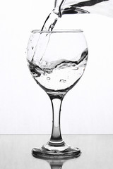 A splash of water in a wineglass on a white background.