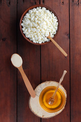 Cottage cheese and cream. Soft cheese and honey on wooden boards. Cottage cheese in pottery. Cream in wooden spoon. Honey on wooden stand. Copy space
