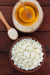 Cottage cheese and cream. Soft cheese and honey on wooden boards. Cottage cheese in pottery. Cream in wooden spoon. Honey on wooden stand. Copy space