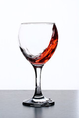 Splash of wine in a wineglass on a white background.