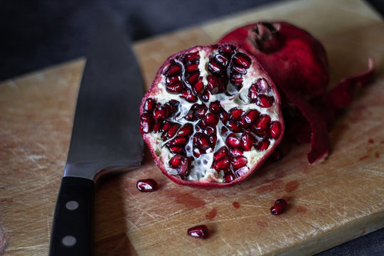 Juicy pomegranate on a cutting board on dark background