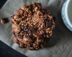 Delicious chocolate chip cookies and cup of milk on dark background