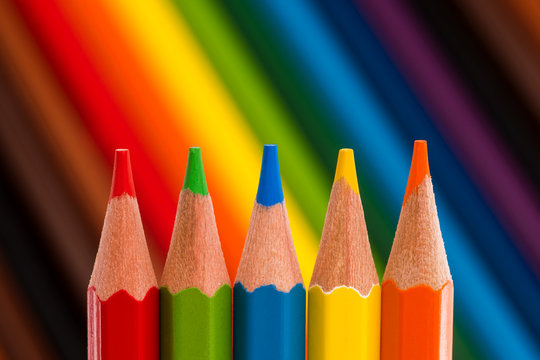 Five colored pencils on colorful background