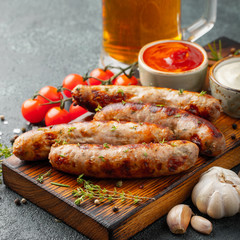 Fried sausages with sauces and herbs on a wooden serving Board. Great beer snack on a dark background