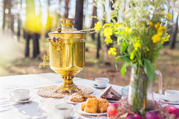 Russian samovar on the table with some snacks outdoors