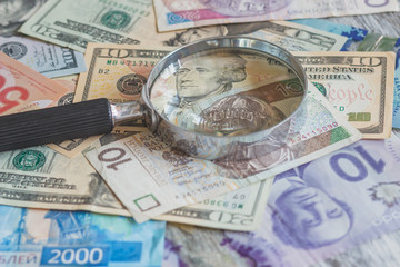 Different currency and a magnifying glass