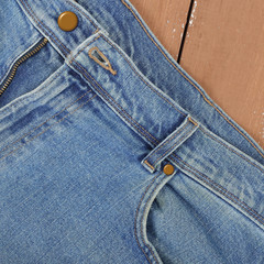 Clothes, shoes and accessories - Top view fragment blue jeans wooden background