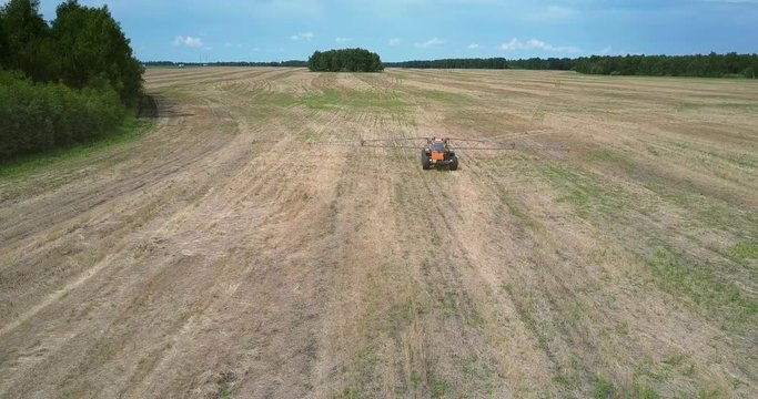 fertilizer spreader moves to camera along harvested field 