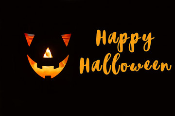 Happy Halloween text sign. Halloween pumpkin with scary glowing face on black background isolated. Jack-o-lantern glowing pumpkin in dark. Season's greeting card