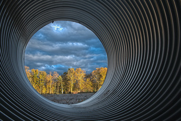 view of sunset woods through large culvert - obrazy, fototapety, plakaty