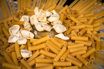 Raw macaroni , spaghetti and ravioli on  plate .