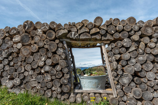 Fototapeta firewood stacked with a window in the center with flowers