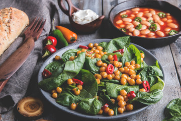 Chickpea and veggies salad with spinach leaves, healthy homemade vegan food, diet. white beans in tomato sauce