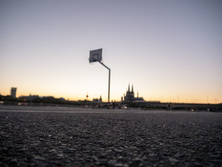 Fototapeta na wymiar Urban Basketball hoop with skyline of Cologne, Germany, in background