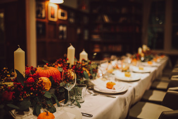 Thanksgiving table setting with automnal decorations, pumpkins, glasses and plates. Holidays,...