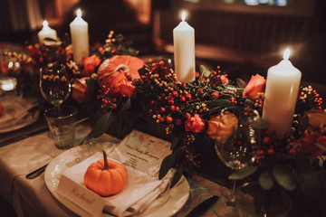 Thanksgiving table setting with automnal decorations, pumpkins, glasses and plates. Holidays, catering and hospitality concept.