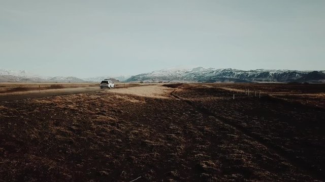 Epic aerial shot of white SUV driving through amazing landscape in Iceland