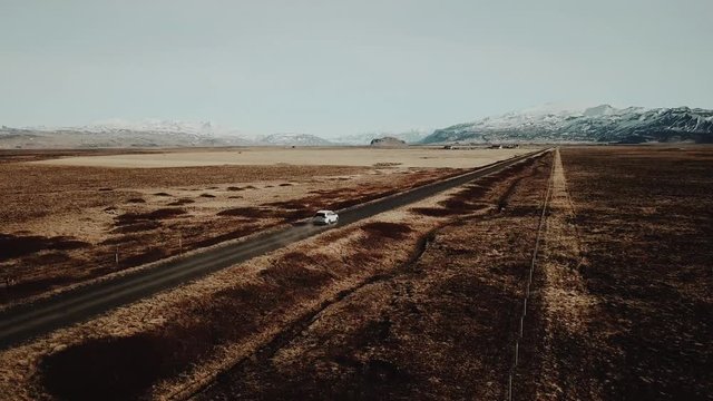 Epic aerial shot of white SUV driving through amazing landscape in Iceland