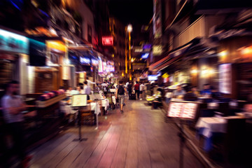 Fototapeta na wymiar Blurry motion image of people walking on a street in Taksim /Beyoglu area at night in Istanbul. Location is a busy nightlife, shopping and dining district.