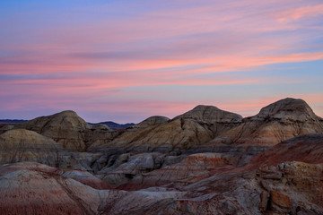 Rainbow Hills in China. Rainbow City, Wucai Cheng. Colorful layered landforms in a remote desert area of Fuyun County. Uygur Autonomous Region, Xinjiang Province. Sunrise - Pink, Purple and Blue Sky