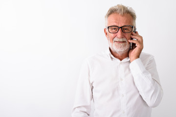 Studio shot of happy senior bearded man smiling while talking on