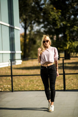 Photographing a girl during autumn near a high-tech glass building with a blurred background of the park