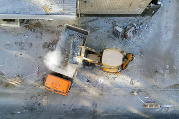 Bulldozer loader uploading waste and debris into dump truck at construction site. building...