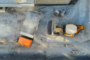 Bulldozer loader uploading waste and debris into dump truck at construction site. building...