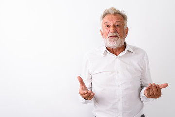 Studio shot of angry senior bearded man with both arms raised ag