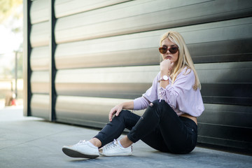 Photographing a girl during autumn near a high-tech glass building with a blurred background of the park