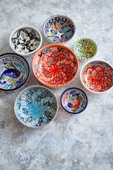 Collection of empty moroccan colorful decorative ceramic bowls. Composition captured from top view, flat lay. Placed on grey stone background.