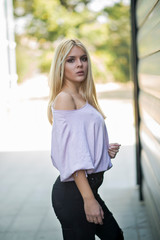 Photographing a girl during autumn near a high-tech glass building with a blurred background of the park