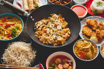 Asian oriental food composition in colorful dishware, served on dark rustic background, top view. Chinese, vietnamese, thai cuisine set. With copy space.