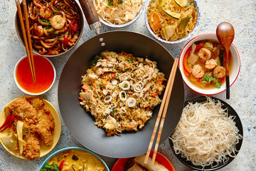 Chinese food set. Chinese noodles, fried rice with chicken, tom yum soup, spring rolls, deep fried fish and udon. Top view. Asian style food concept composition.