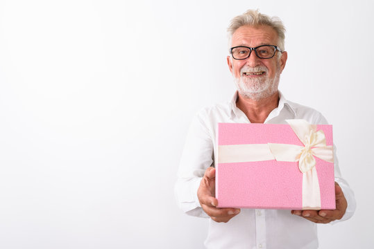 Studio shot of happy senior bearded man smiling and giving gift 
