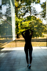 Photographing a girl during autumn near a high-tech glass building with a blurred background of the park