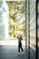 Photographing a girl during autumn near a high-tech glass building with a blurred background of the park