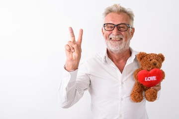 Studio shot of happy senior bearded man smiling and giving peace
