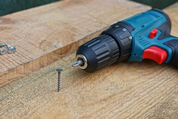 one gray screw in a wooden board and a screwdriver