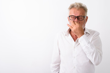 Studio shot of senior bearded man covering nose and looking disg