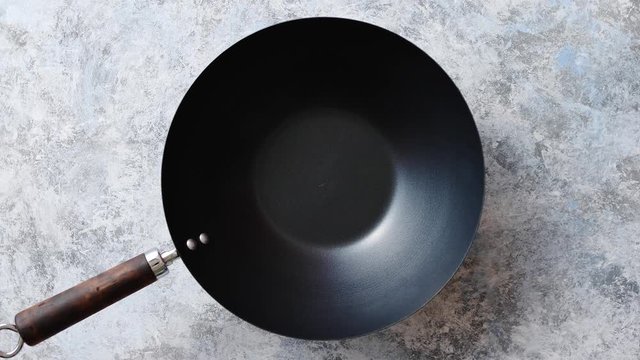Traditional empty black iron wok pan placed on stone background. Top view.