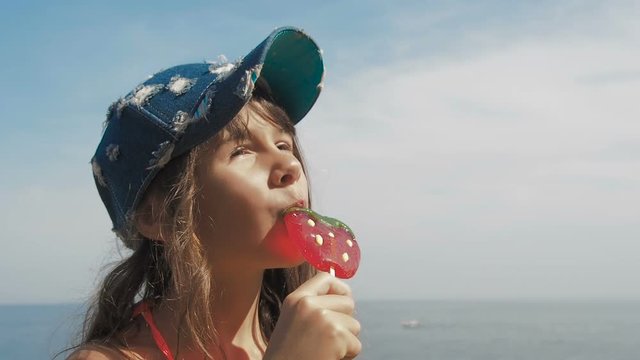 Child on the beach with a lollipop. The girl is enjoying the candy.
