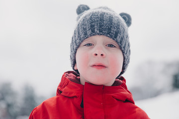 portrait of a sad boy in winter hat. frustrated child on a winter day on a mountain slope