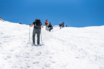 People doing trekking inside Andes valleys, crossing a snow valleys in central Chile at Cajon del Maipo, Santiago de Chile, amazing views over mountains and glaciers with awesome hiking exploration