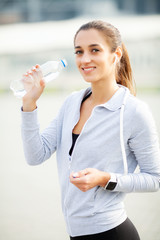 Sport outdoor. Sportive woman in headphones drinking water