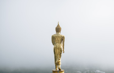 Wat Phra That Khao Noi, Nan Province, Thailand, the Golden Buddha statue standing on a mountain with the mist in early moring,City of cultural and natural tourism in the