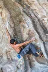 The last movements to reach the summit by a male climber. Rock climbing inside the Andes mountains at Cajon del Maipo, Chile. Climber solving the movements of 